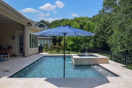 Backyard swimming pool with water feature and umbrella - Pulliam Pools.