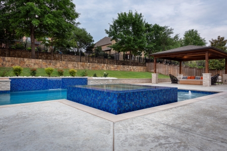 geometric pool with wall and jacuzzi.